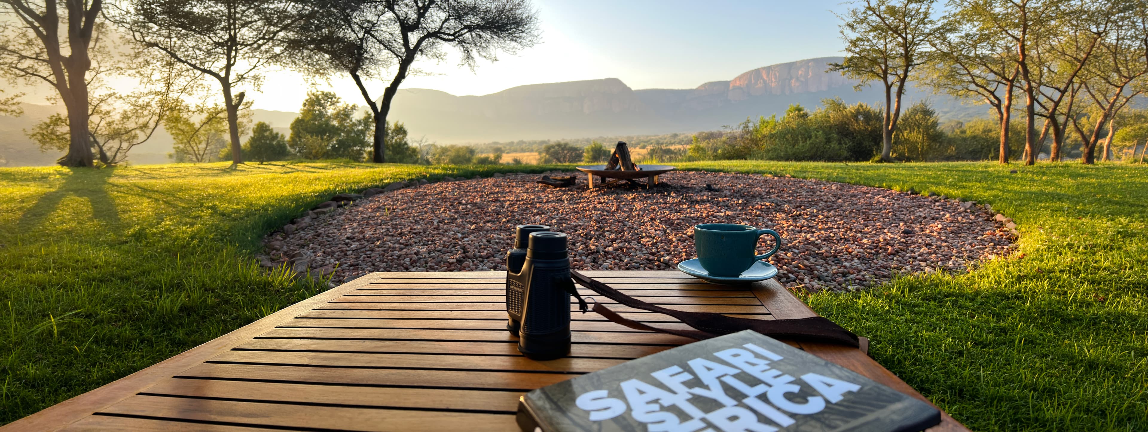 Safari landscape at golden hour — binoculars, coffee, and an acacia view